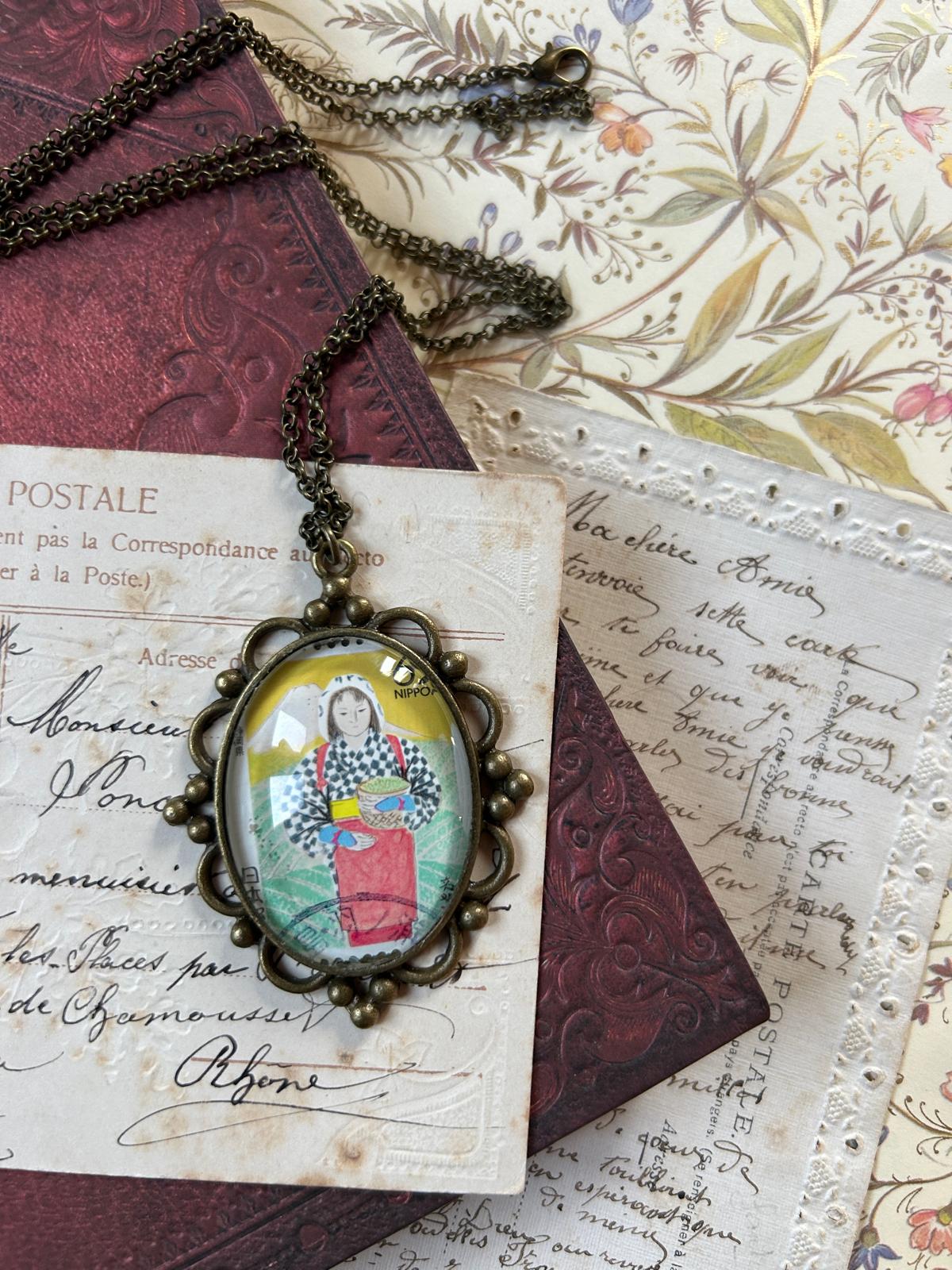 Collana con ciondolo ovale e francobollo giapponese: una donna raccoglie il tè con il Monte Fuji sullo sfondo