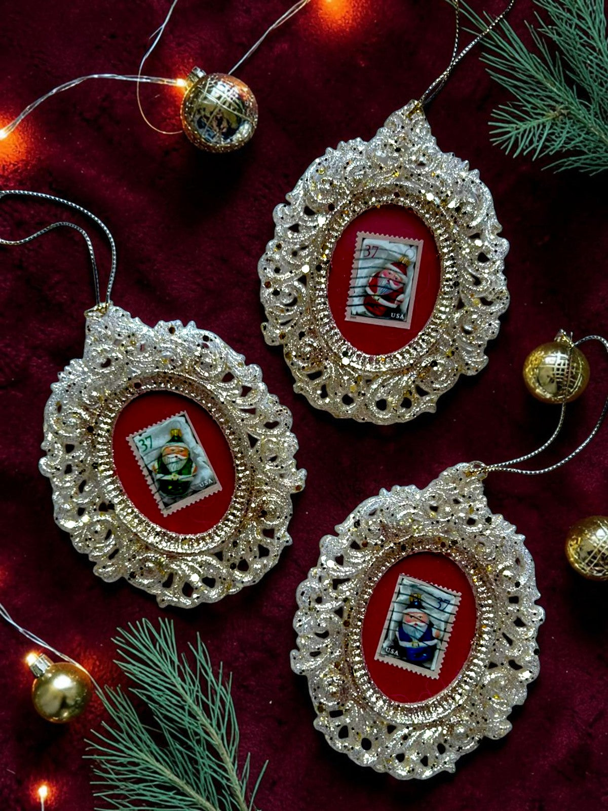 Tre addobbi natalizi artigianali italiani con Babbo Natale verde, rosso e blu su velluto rosso