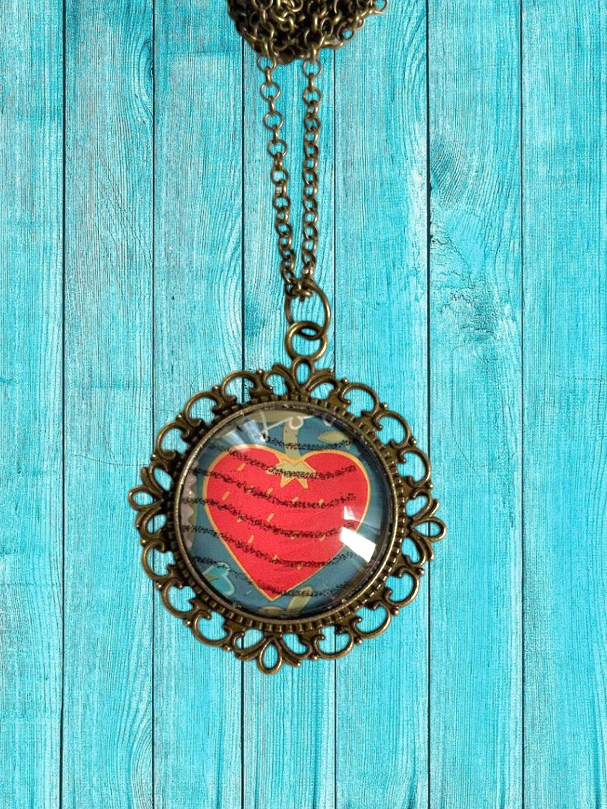 Ciondolo tondo artigianale italiano con francobollo di un cuore rosso dell'amore, cornice bronzo traforata