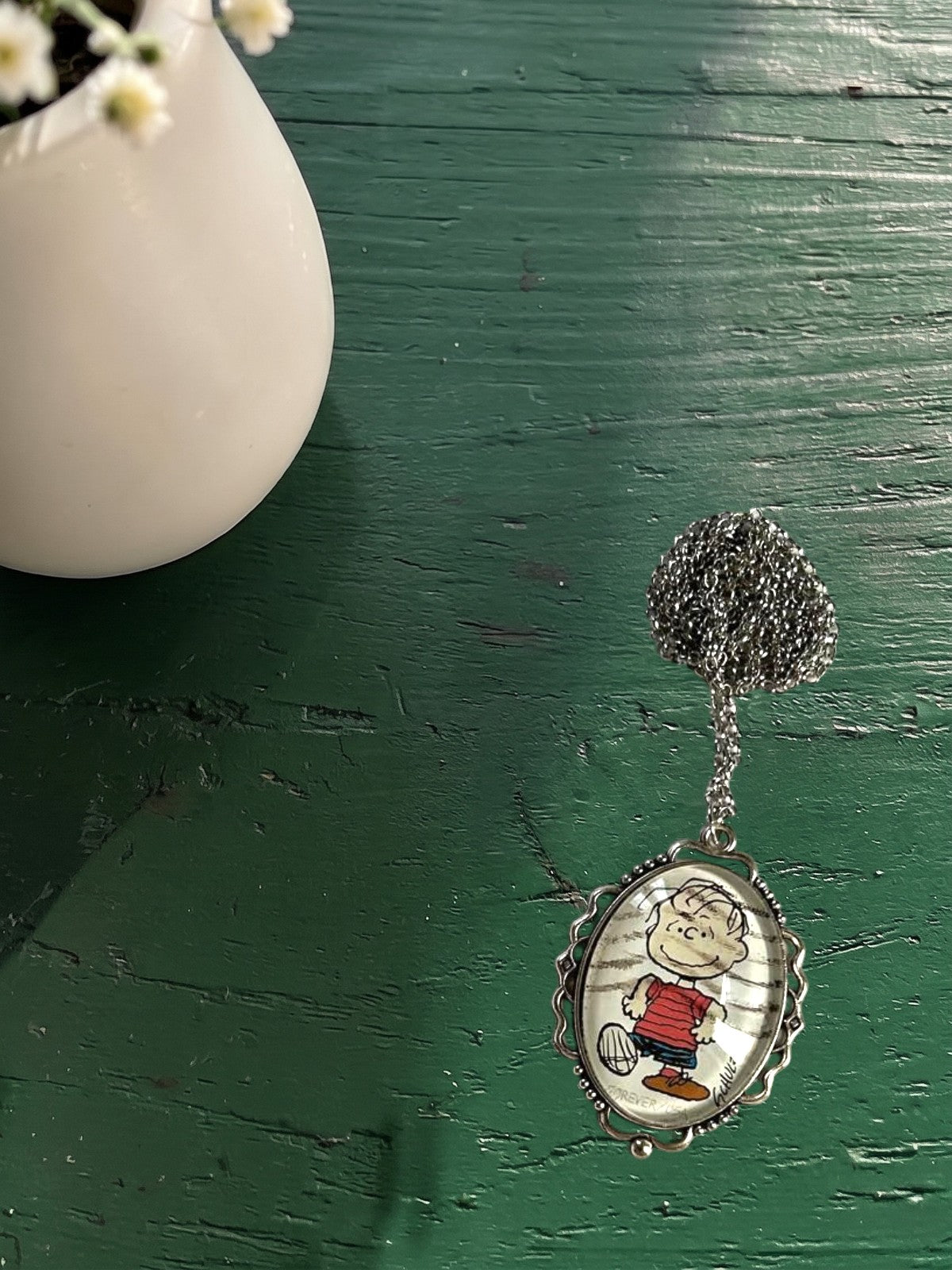 Collana artigianale con francobollo americano di Linus dei Peanuts, flatlay con ciondolo ovale argentato, Italia