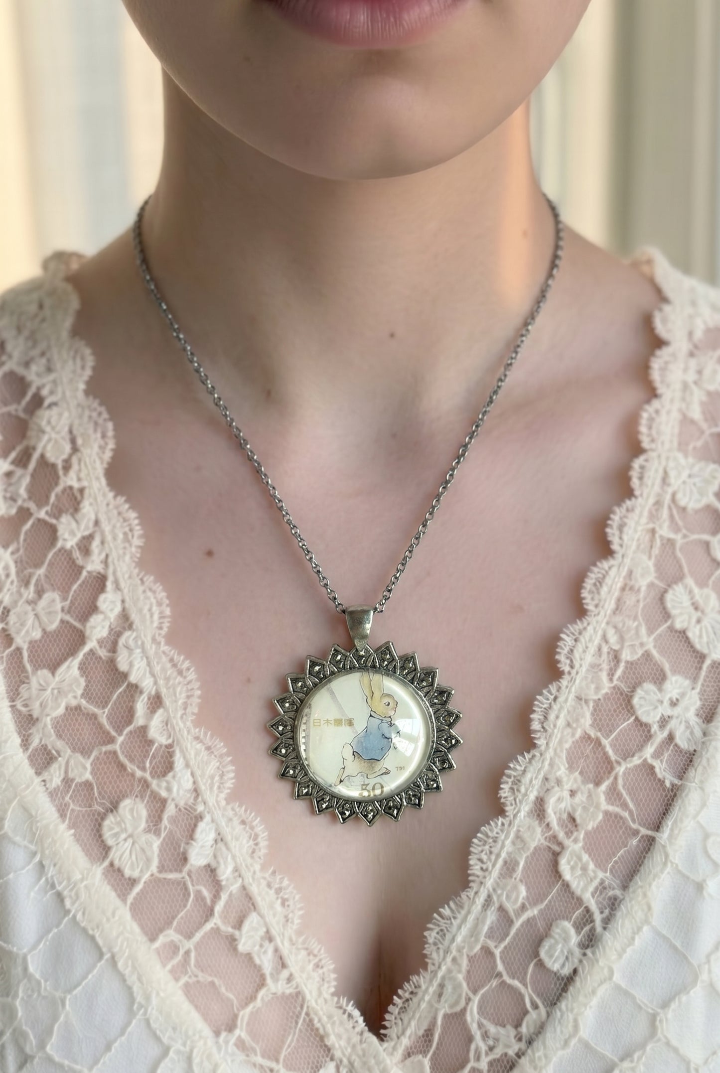 Collana con francobollo giapponese di Peter Coniglio di Beatrix Potter che corre, cornice tonda in argento a raggiera, indossata