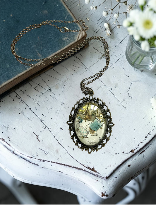 Collana con francobollo d'epoca inglese del 1979 di Peter Rabbit di Beatrix Potter, cornice ovale in bronzo a filigrana, su tavolo