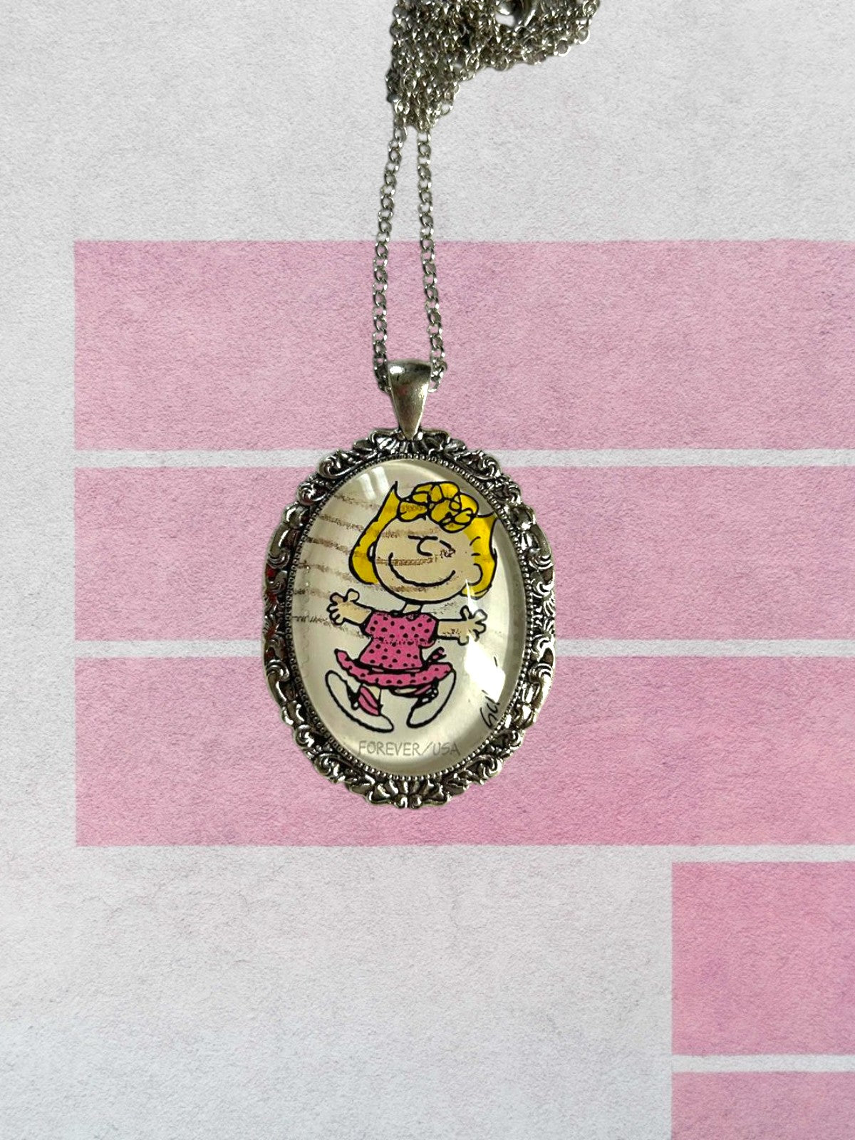 Collana artigianale con francobollo americano di Sally dei Peanuts, flatlay con ciondolo ovale argentato, Italia