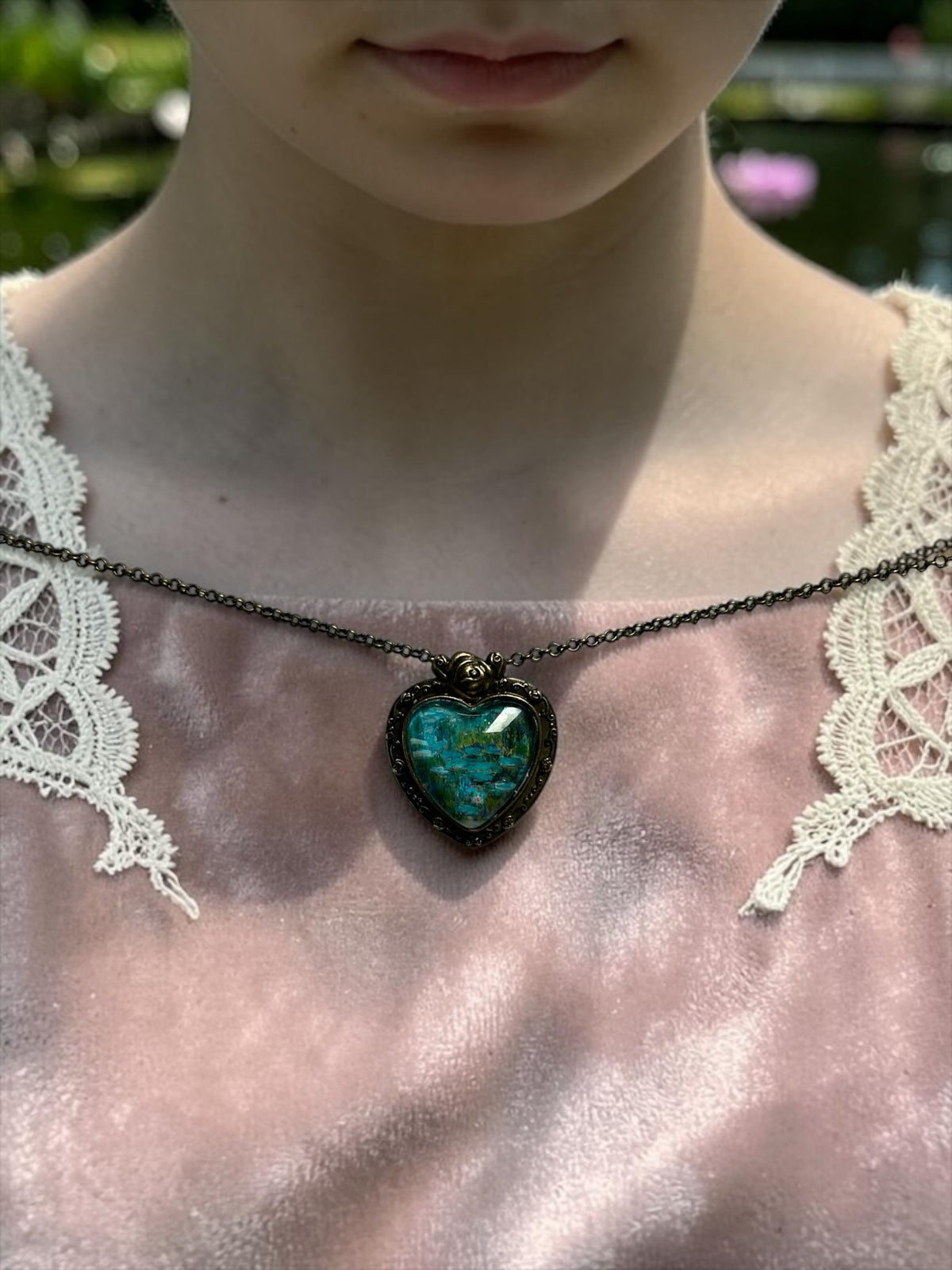 Collana artigianale a cuore con francobollo Ninfee di Monet Sierra Leone 2015, indossata su abito rosa, arte, Italia