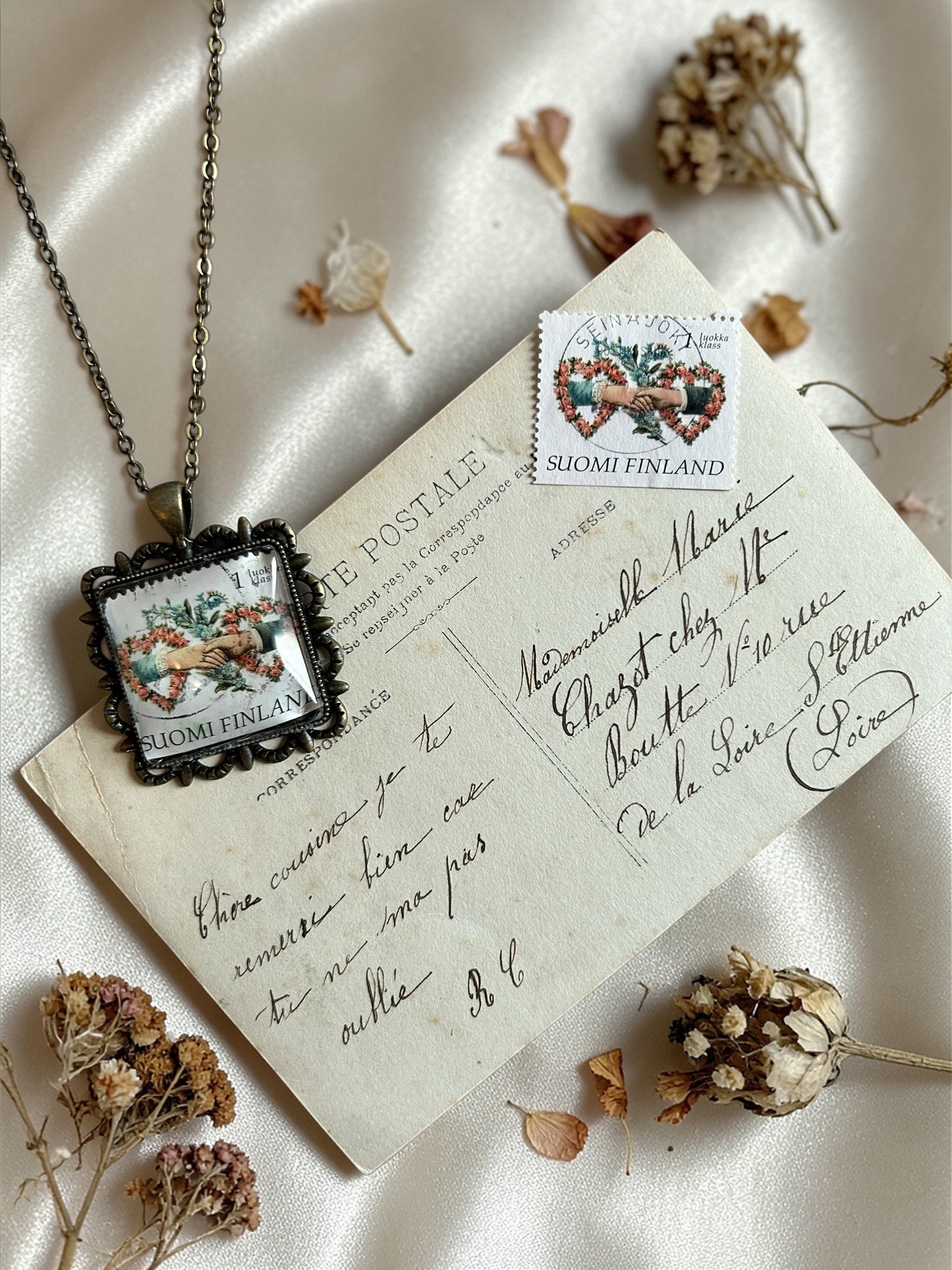 collana con romantico francobollo finlandese con due mani e cuori di fiori