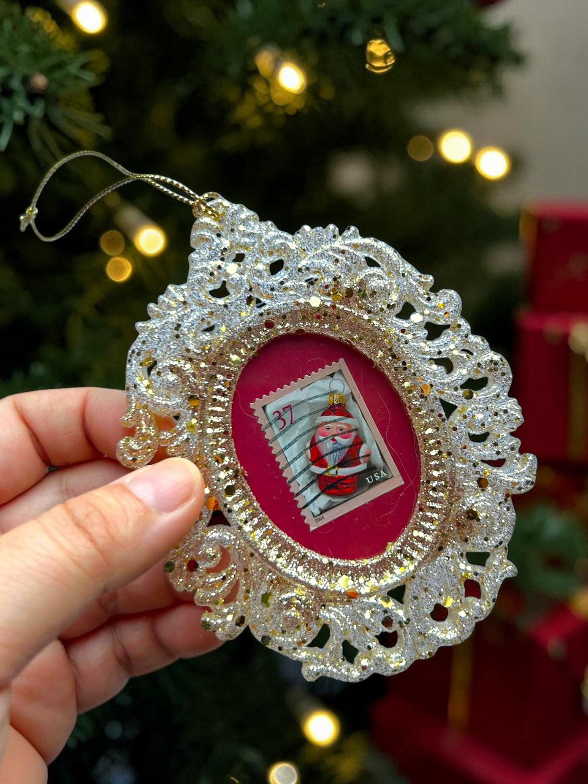 Addobbo natalizio rosso fatto a mano in Italia, tenuto in mano davanti a un albero di Natale con luci