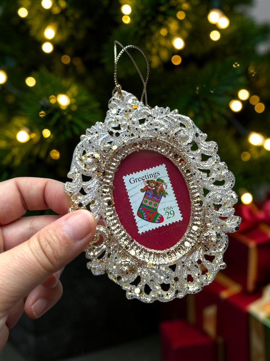 Addobbo natalizio artigianale italiano con calza di Natale su francobollo d'epoca, tenuto in mano davanti all'albero
