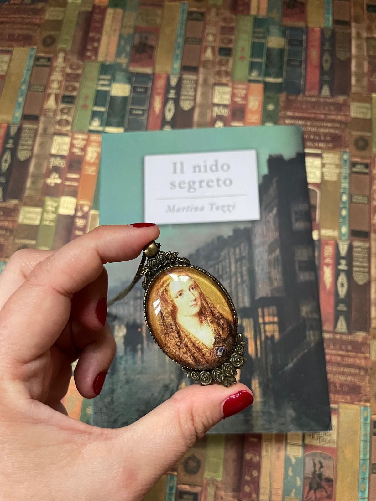 Ciondolo ovale in bronzo con il ritratto di Mary Shelley tenuto in mano, cornice lavorata a rose