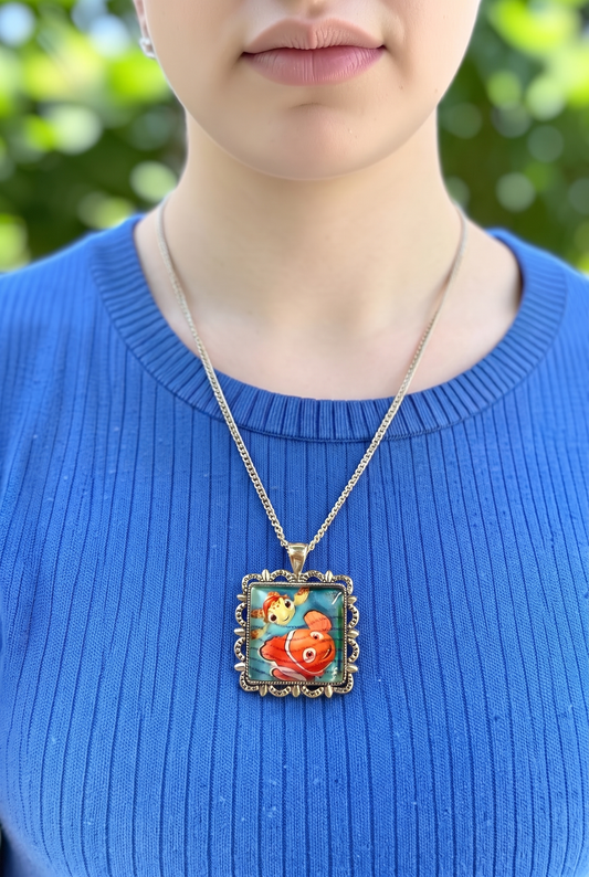 Collana artigianale indossata con francobollo americano di Alla ricerca di Nemo, Nemo e Guizzo, montatura argentata, Italia