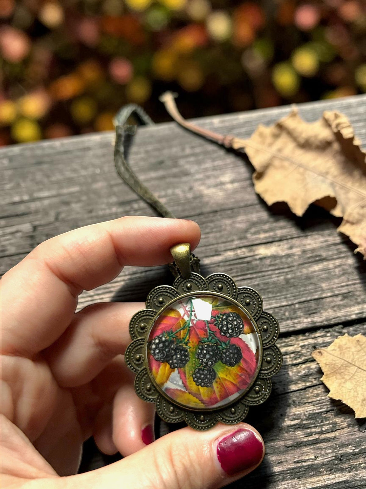 Collana artigianale italiana con ciondolo ovale a more autunnali, da francobollo inglese del 1993, tenuta in mano