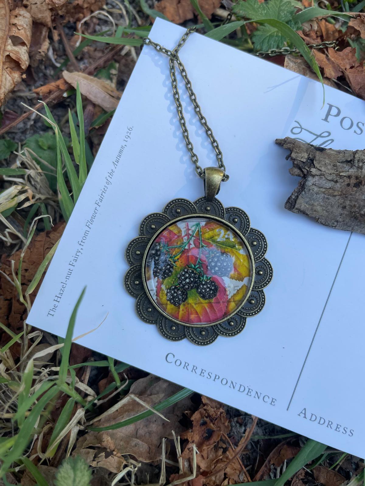 Collana artigianale con ciondolo tondo in bronzo e francobollo d'epoca con more d'autunno, fatta a mano in Italia