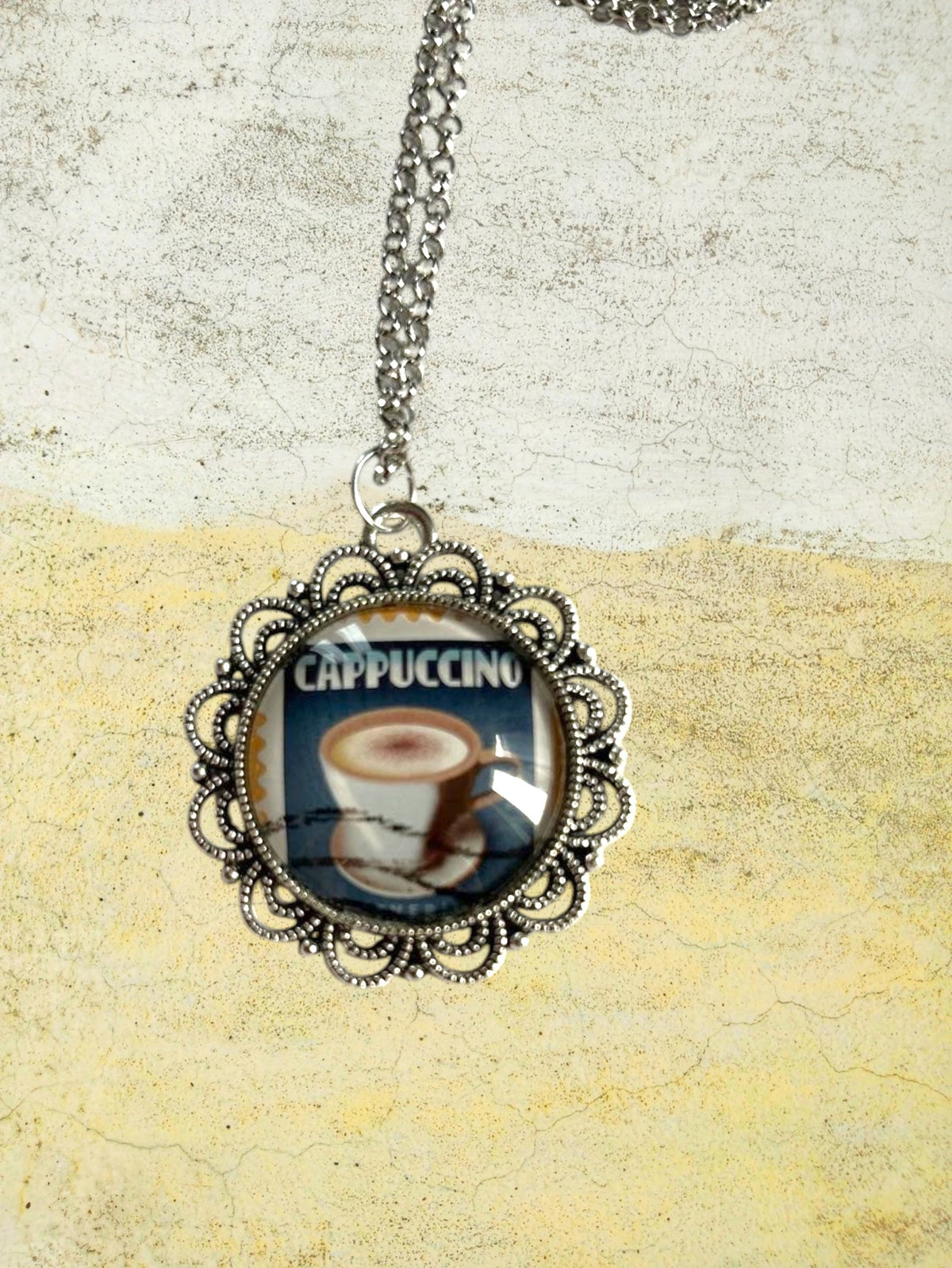 Ciondolo tondo artigianale italiano con francobollo americano del cappuccino su fondo giallo cornice argentata