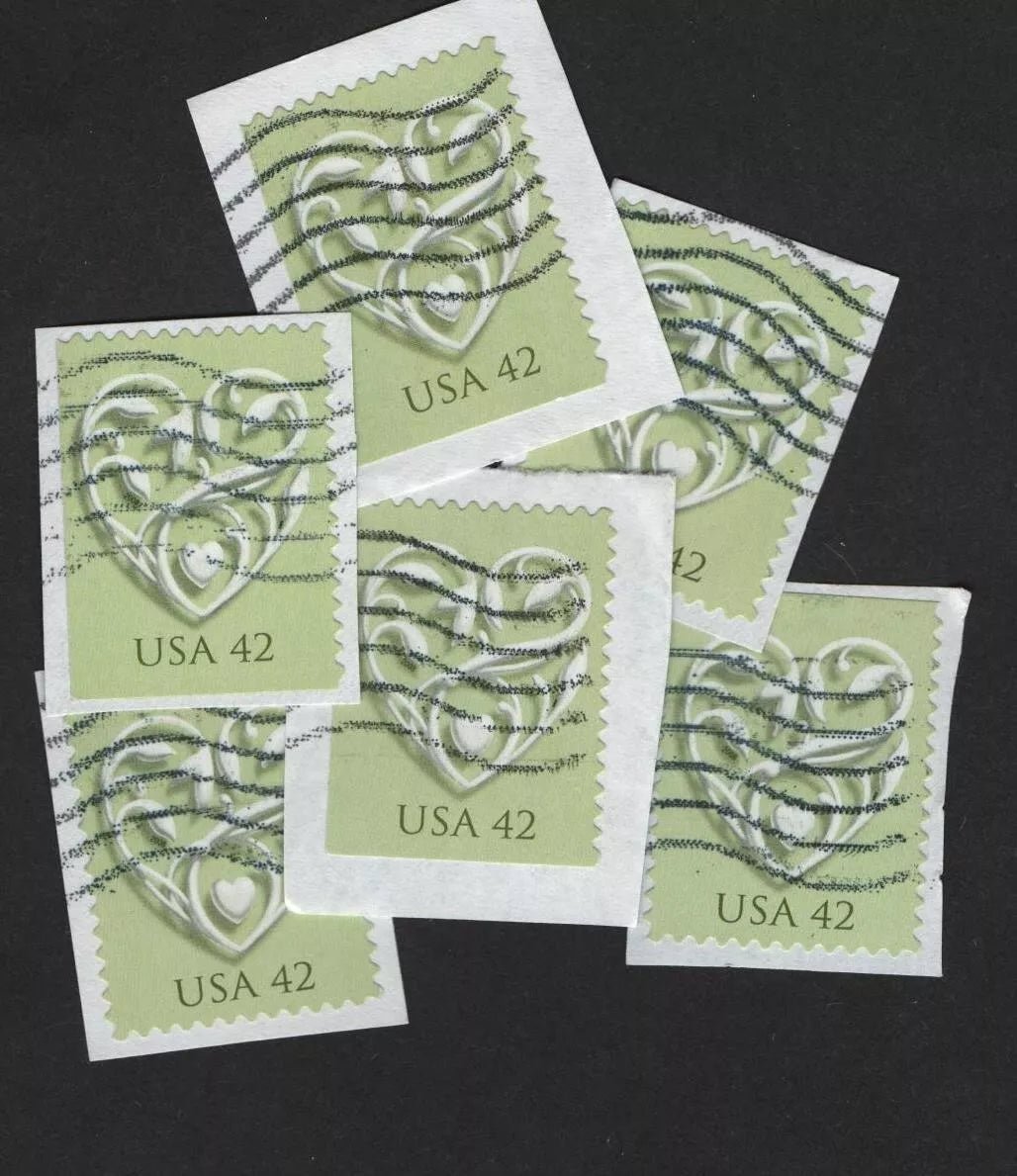 Francobolli con cuore bianco su sfondo verde, ancora sulla carta della busta da cui sono stati ritagliati, artigianato, Italia
