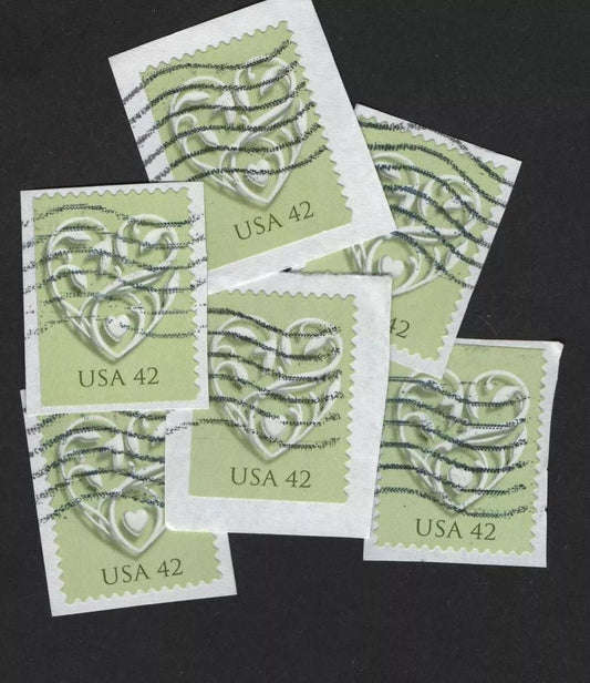 Francobolli con cuore bianco su sfondo verde, ancora sulla carta della busta da cui sono stati ritagliati