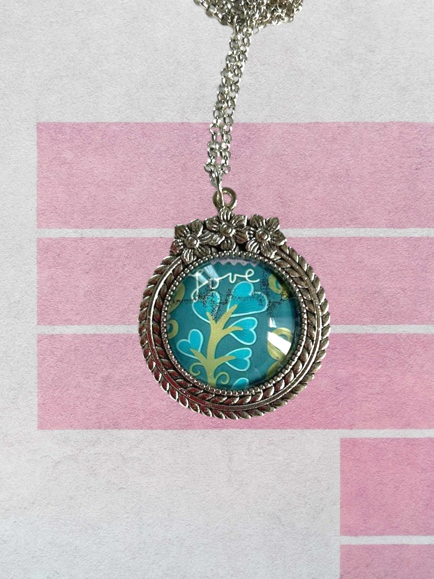 Collana artigianale indossata con francobollo americano di un fiore turchese, cornice argentata a fiori, Italia