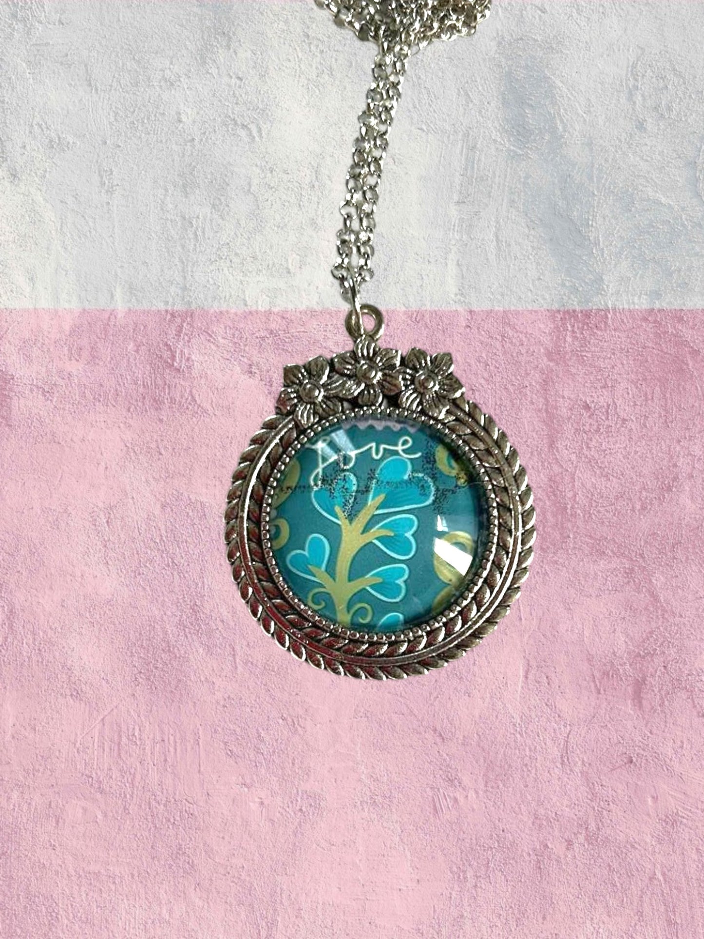 Collana artigianale indossata con francobollo americano di un fiore turchese, cornice argentata a fiori, Italia