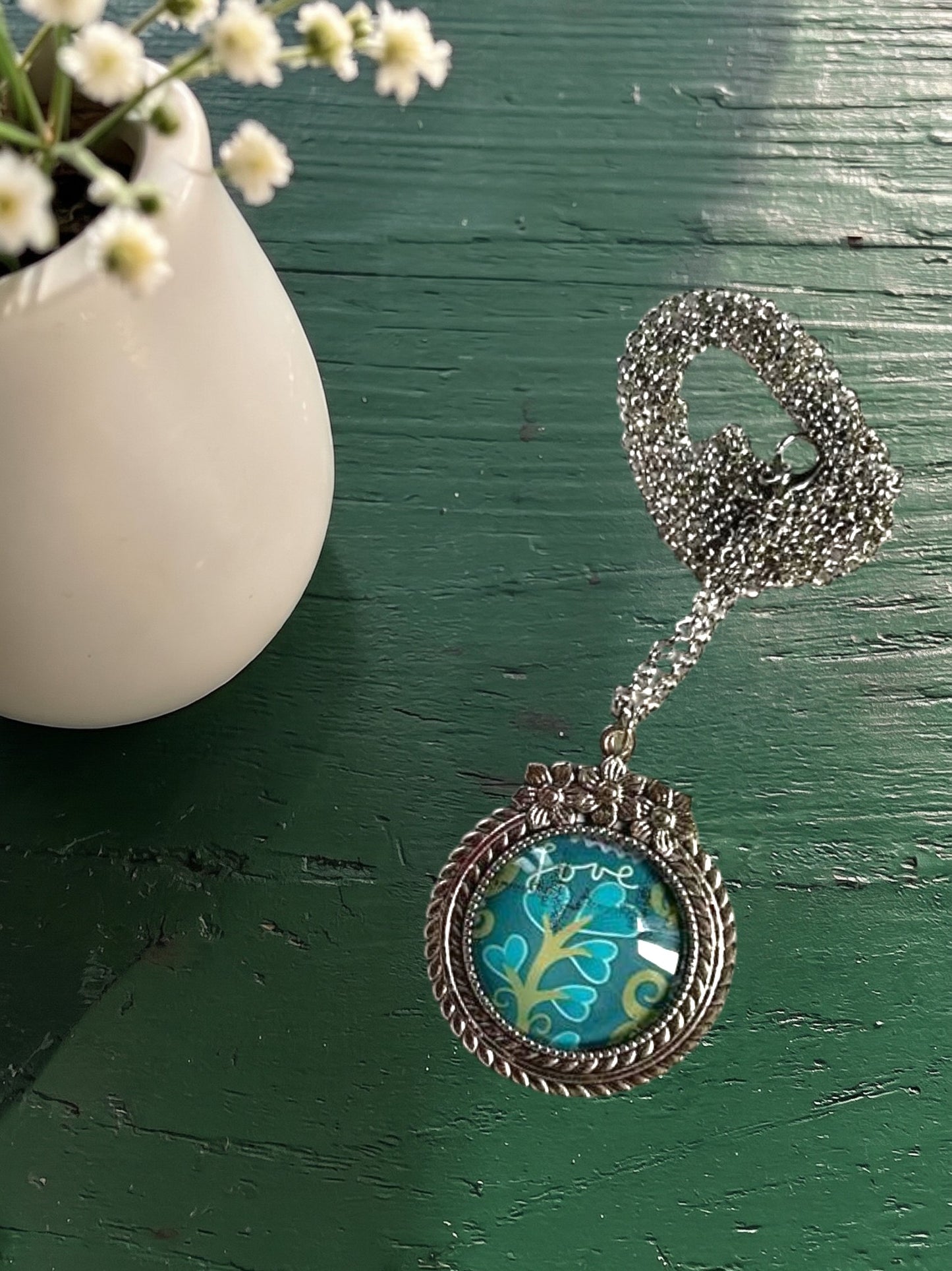 Collana artigianale indossata con francobollo americano di un fiore turchese, cornice argentata a fiori, Italia