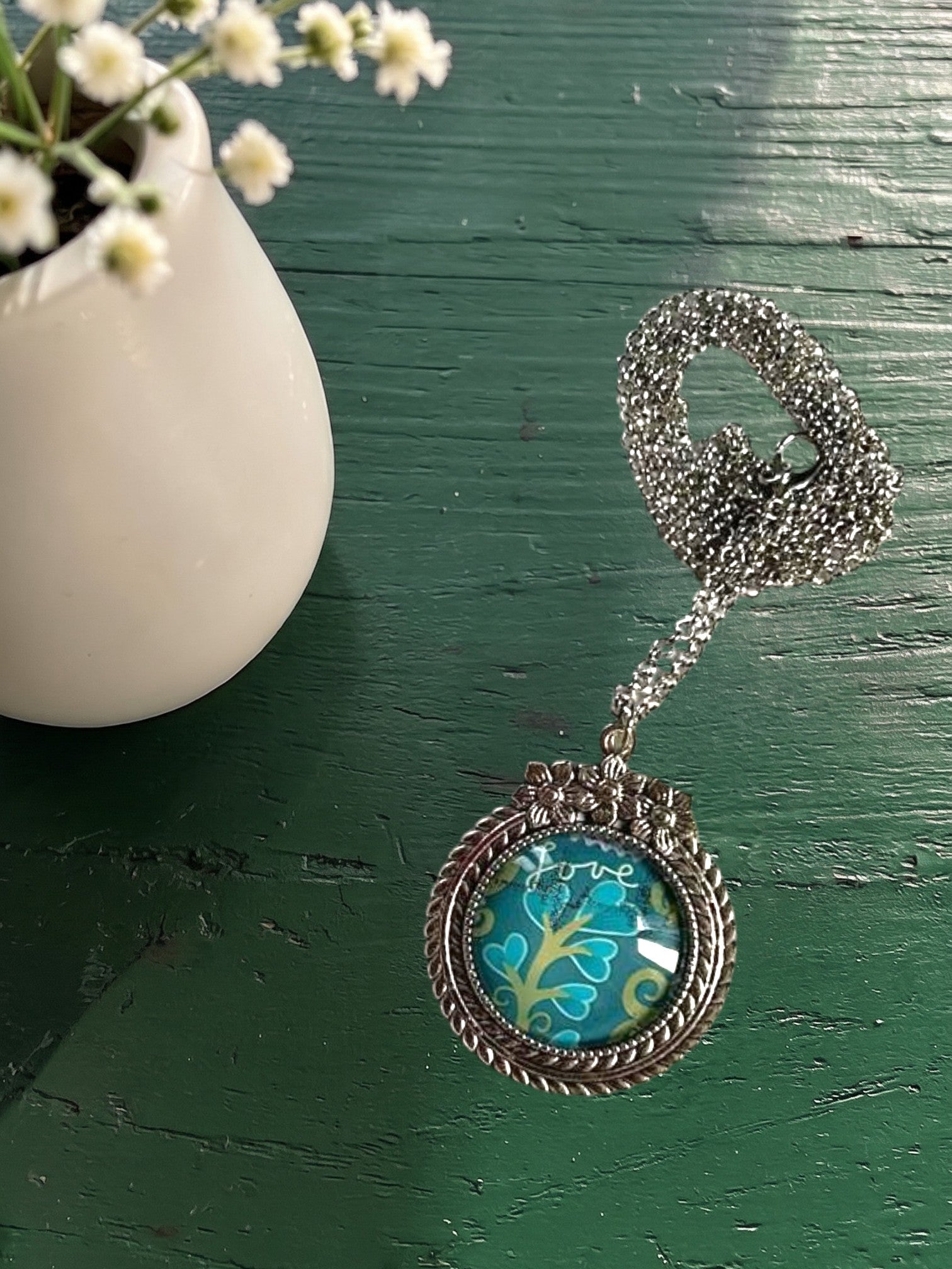 Collana artigianale indossata con francobollo americano di un fiore turchese, cornice argentata a fiori, Italia