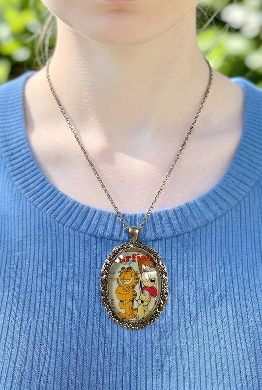 Collana artigianale indossata con francobollo americano di Garfield, il gatto rosso, e Odie, cornice ovale argentata, Italia