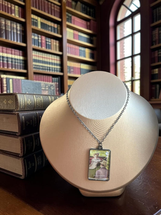 Collana Jane Austen con il francobollo Royal Mail del 2013 dedicato a Emma, illustrato da Angela Barrett, incastonato in una montatura rettangolare di metallo scuro. La collana è indossata su un busto.