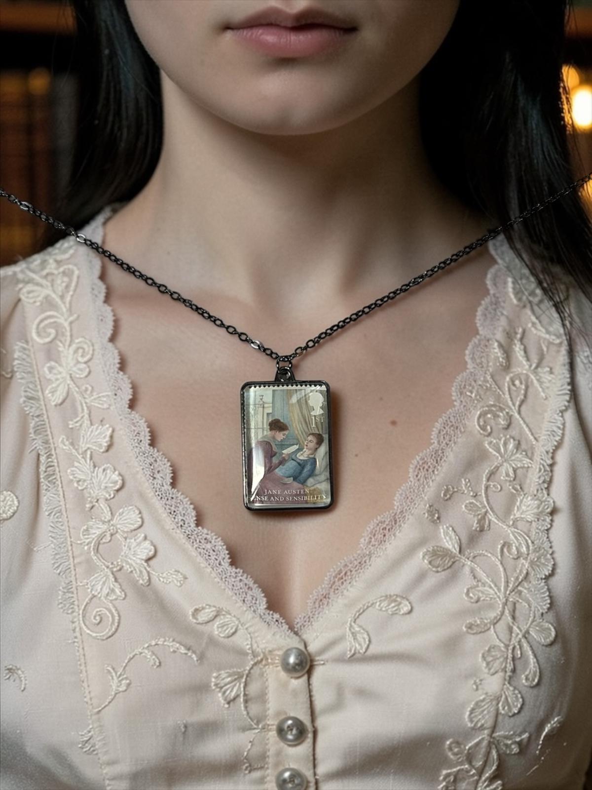 Il ciondolo rettangolare in metallo scuro della collana Jane Austen Ragione e Sentimento, con il francobollo Royal Mail del 2013 incastonato al centro, indossato su un busto.