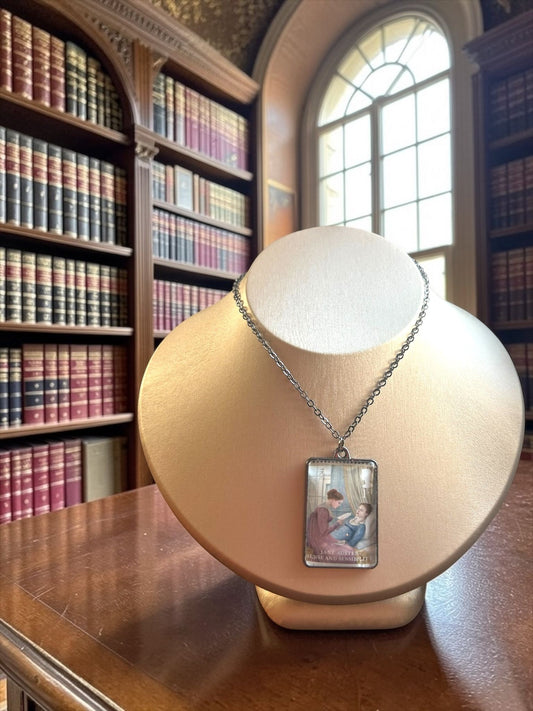 Collana Jane Austen con il francobollo Royal Mail del 2013 dedicato a Ragione e Sentimento, illustrato da Angela Barrett, incastonato in una montatura rettangolare di metallo scuro. La collana è indossata su un busto.