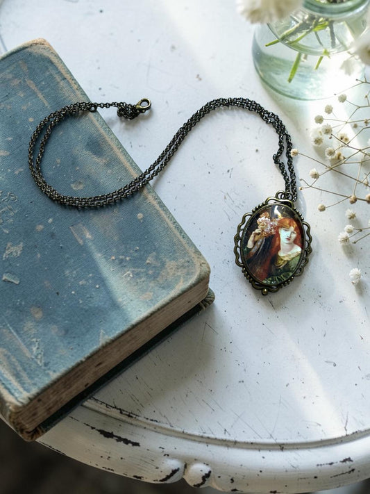 La Ghirlandata di Rossetti su ciondolo ovale in bronzo, collana preraffaellita fotografata in piano con fiori e dettagli