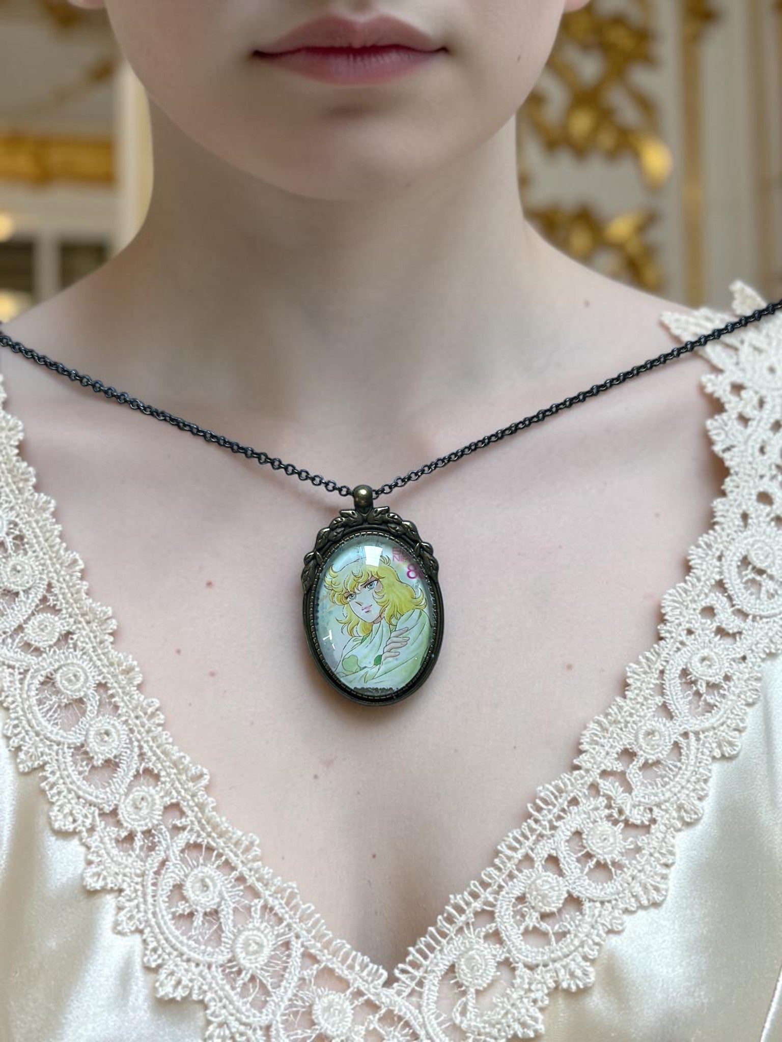 Collana con ciondolo ovale e francobollo giapponese di Oscar indossata su abito di pizzo crema, da Lady Oscar