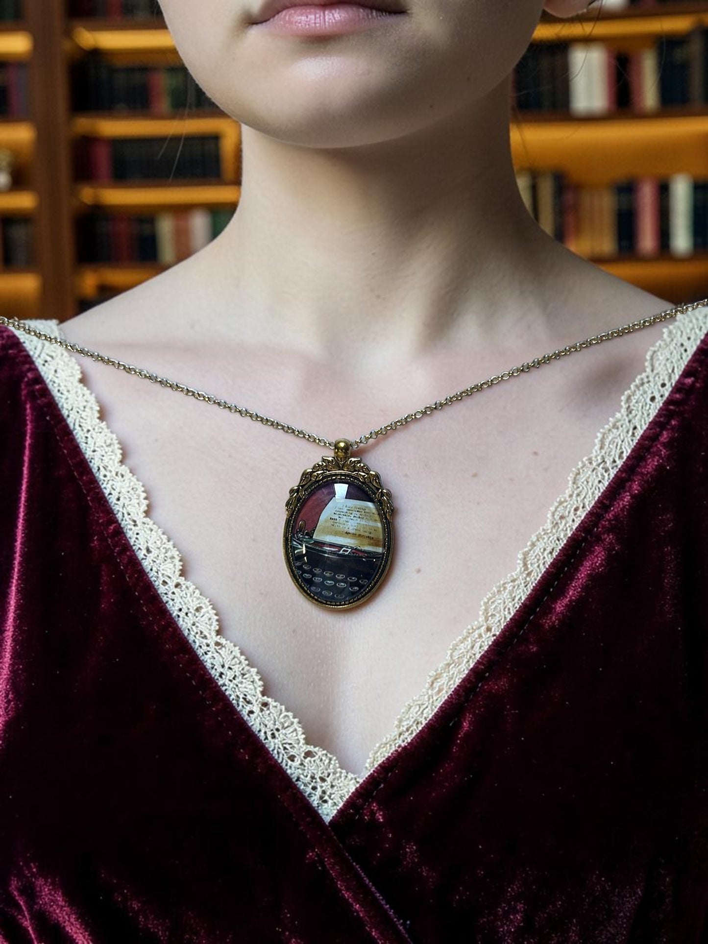  Collana indossata con ciondolo ovale e francobollo della macchina da scrivere di Agatha Christie, abito bordeaux