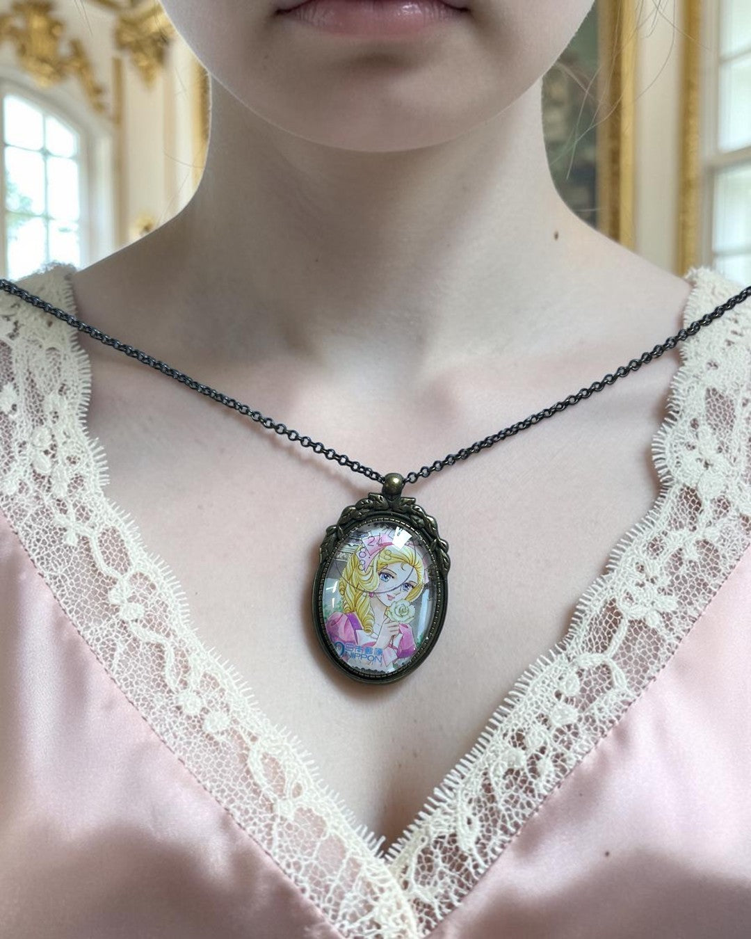 Collana con ciondolo ovale bronzeo e francobollo giapponese di Maria Antonietta indossata su top rosa, da Lady Oscar