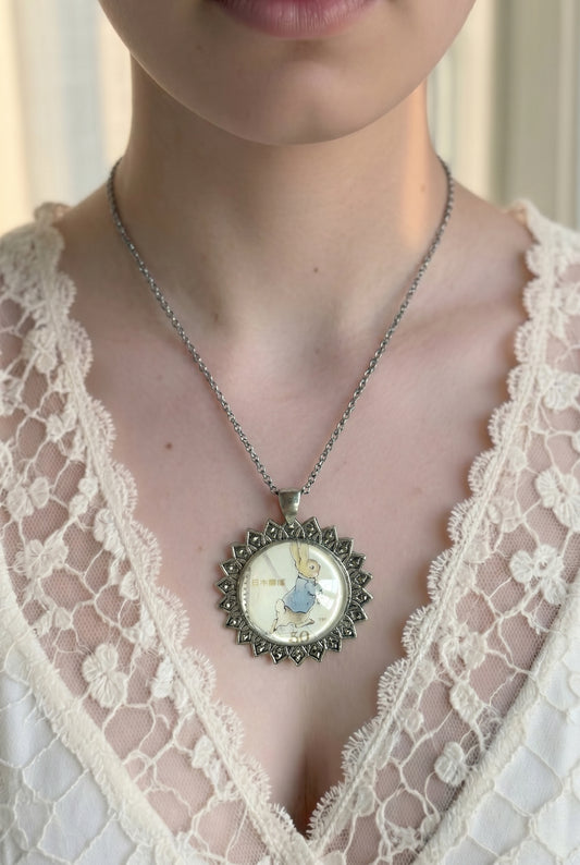 Collana con francobollo giapponese di Peter Coniglio di Beatrix Potter che corre, cornice tonda in argento a raggiera, indossata