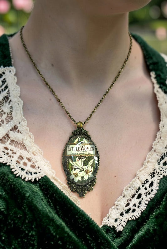 Collana indossata con ciondolo ovale e copertina vintage di Piccole Donne (Little Women), cornice color bronzo con rose