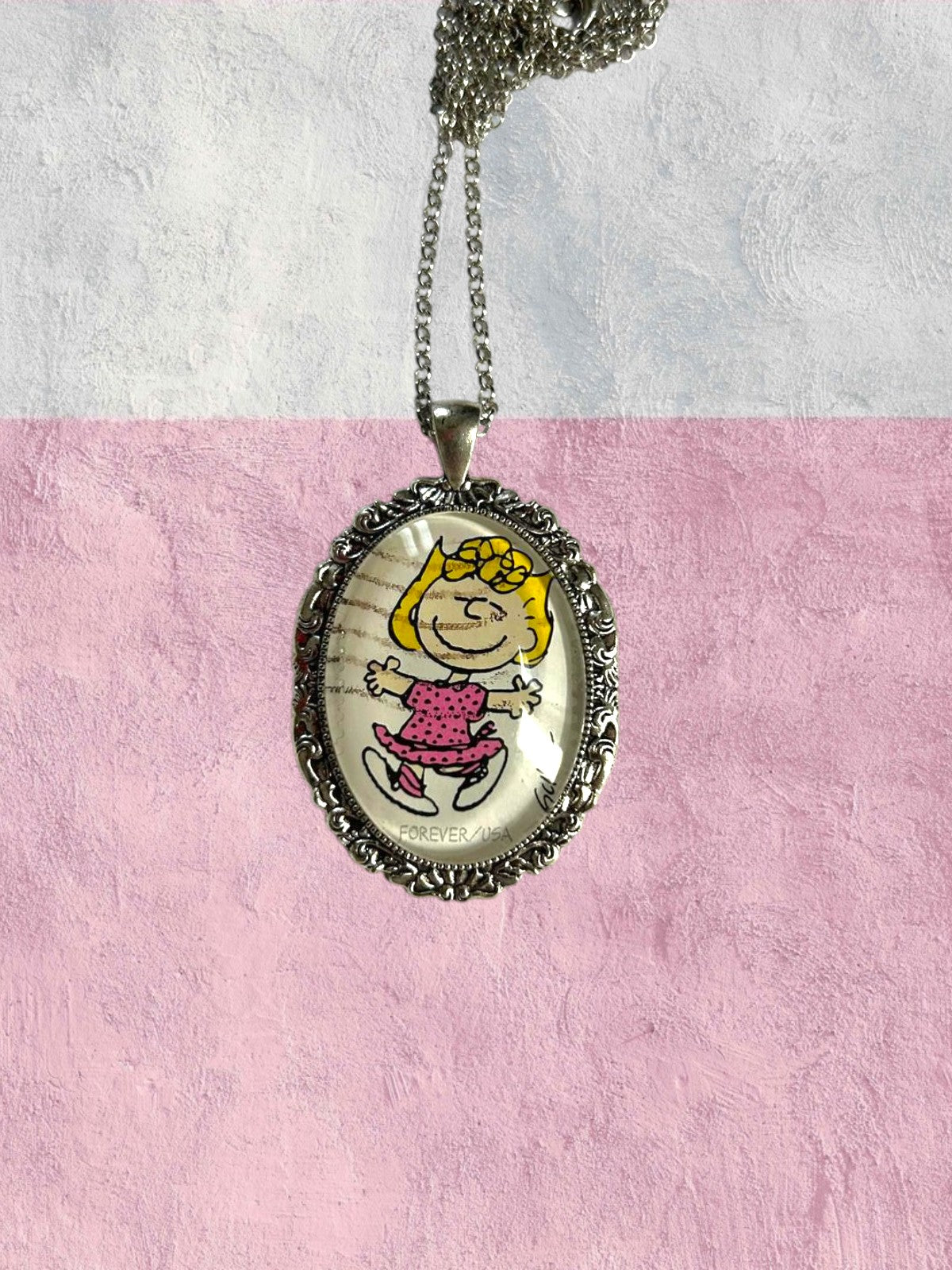 Dettaglio della collana artigianale con francobollo americano di Sally dei Peanuts, creata in Italia