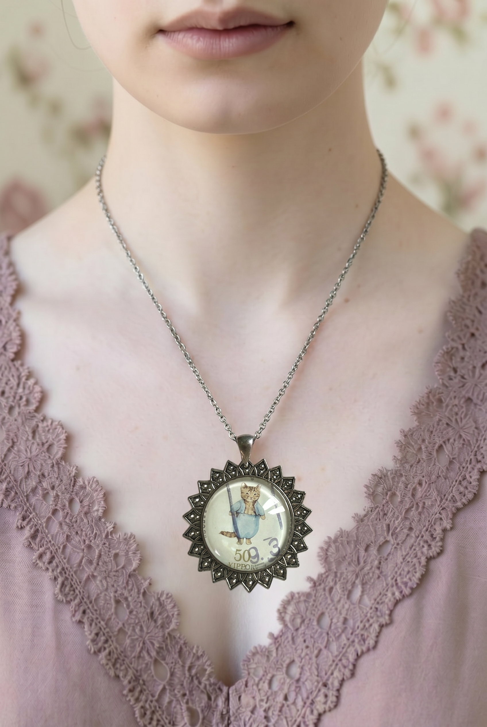 Collana con francobollo giapponese di Tom Kitten, il gattino di Beatrix Potter in completo azzurro, cornice tonda in argento a raggiera, indossata