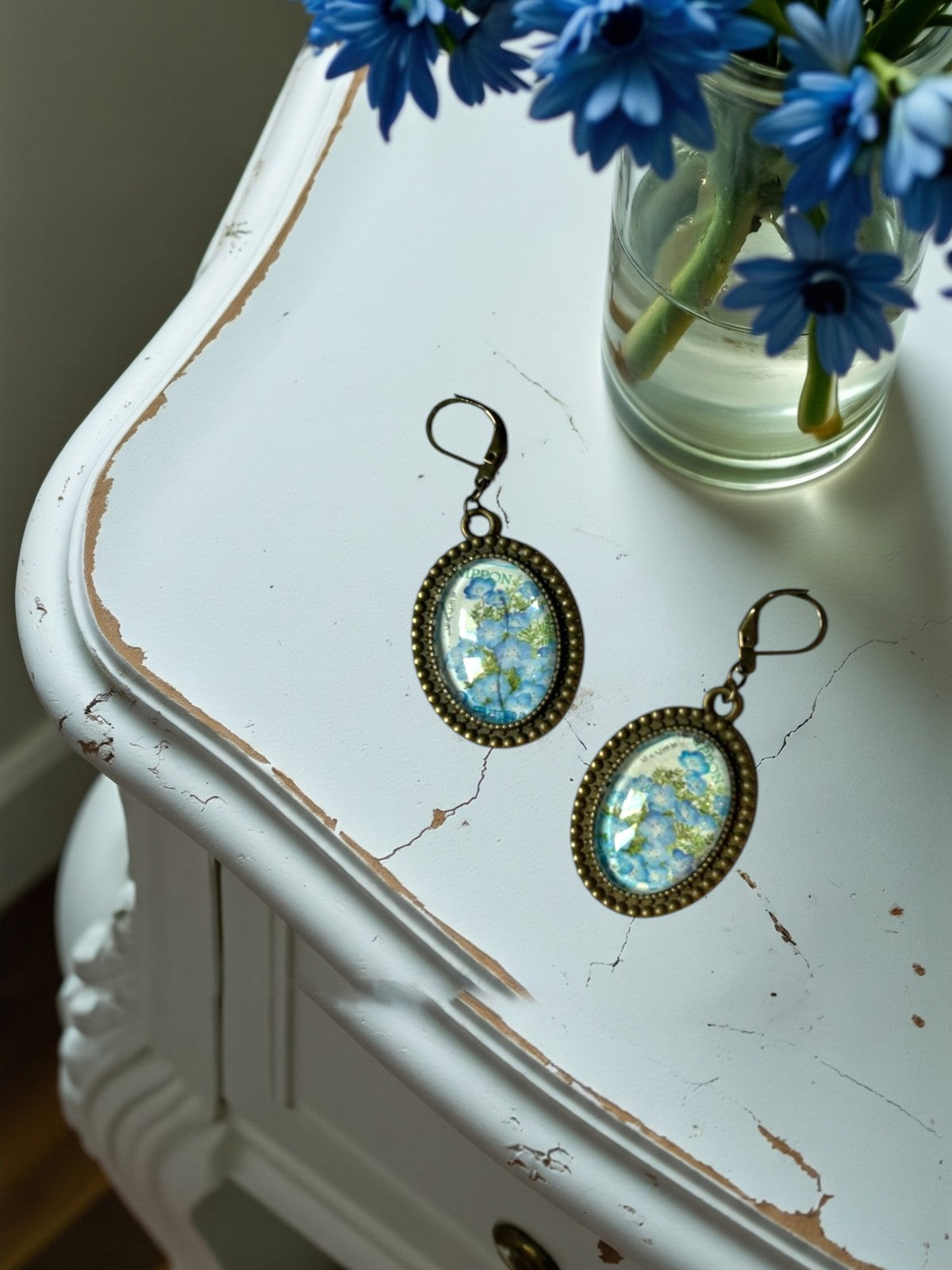 Orecchini artigianali con fiori azzurri nemofila da francobollo, montatura ovale color bronzo a perline,
realizzati in Italia