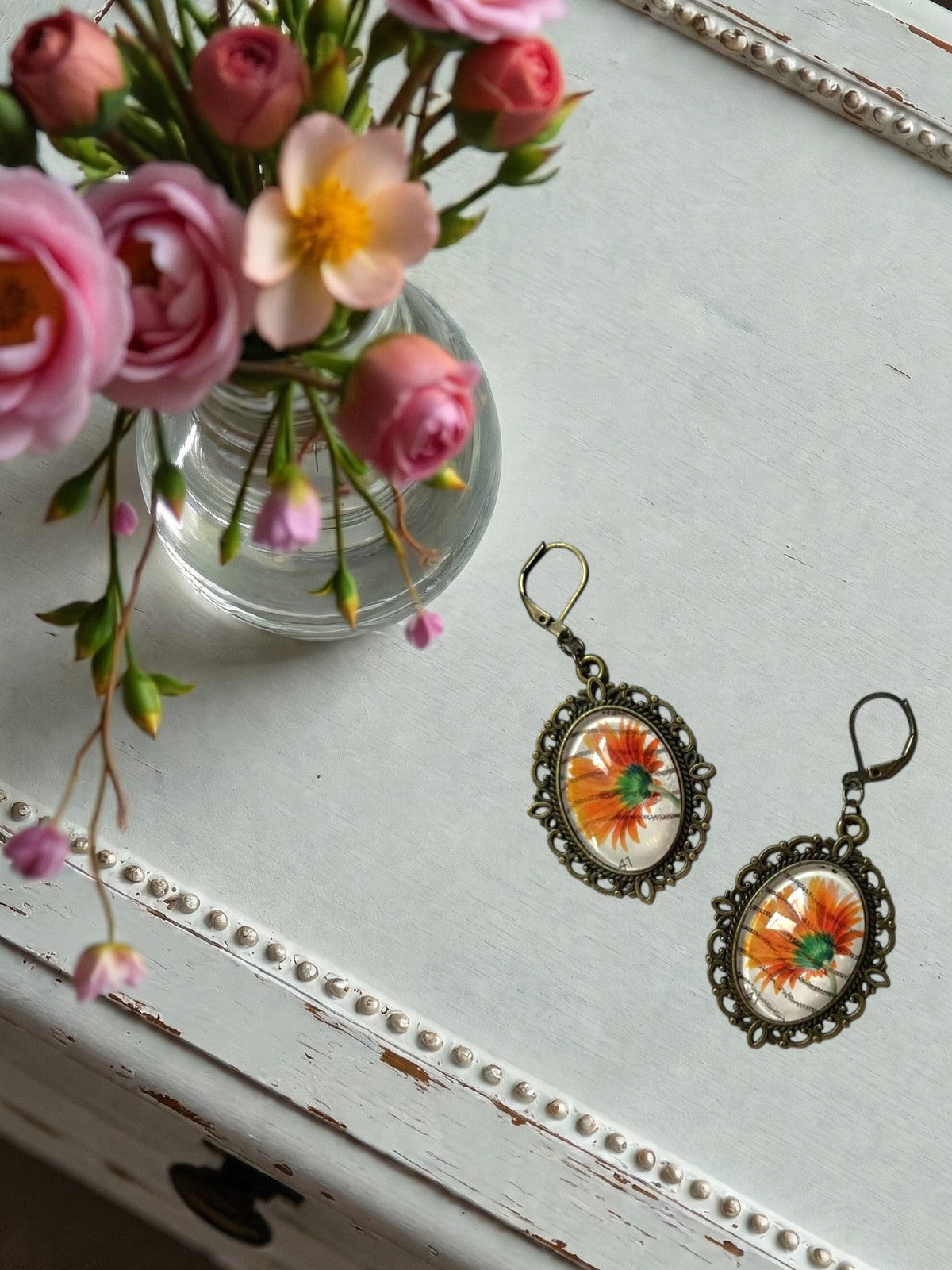 Orecchini artigianali con gerbera arancione da francobollo, montatura ovale color bronzo traforata,
realizzati in Italia