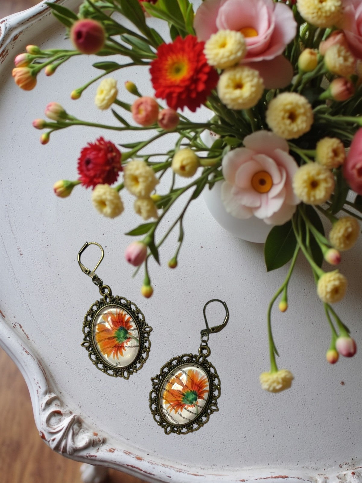 Orecchini artigianali con gerbera arancione da francobollo, montatura ovale color bronzo traforata,
realizzati in Italia