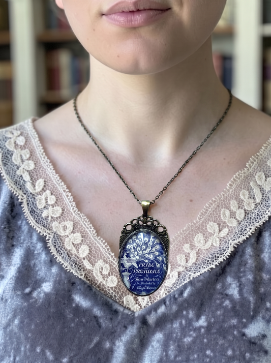 Collana artigianale italiana indossata su blusa di pizzo bianco, ciondolo ovale con la copertina di Orgoglio e pregiudizio