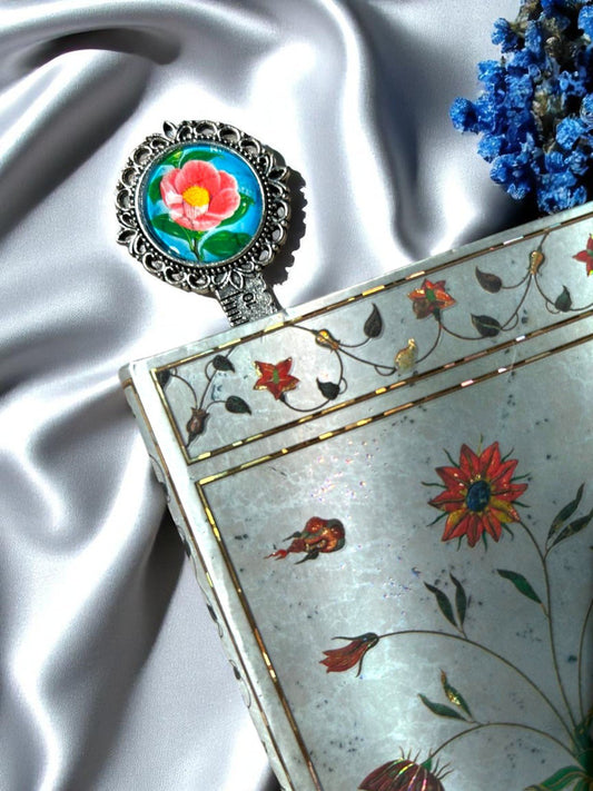 Segnalibro con una camelia giapponese, da un francobollo vintage dal fondo blu. Il fiore che sboccia tra inverno e primavera, tra le pagine