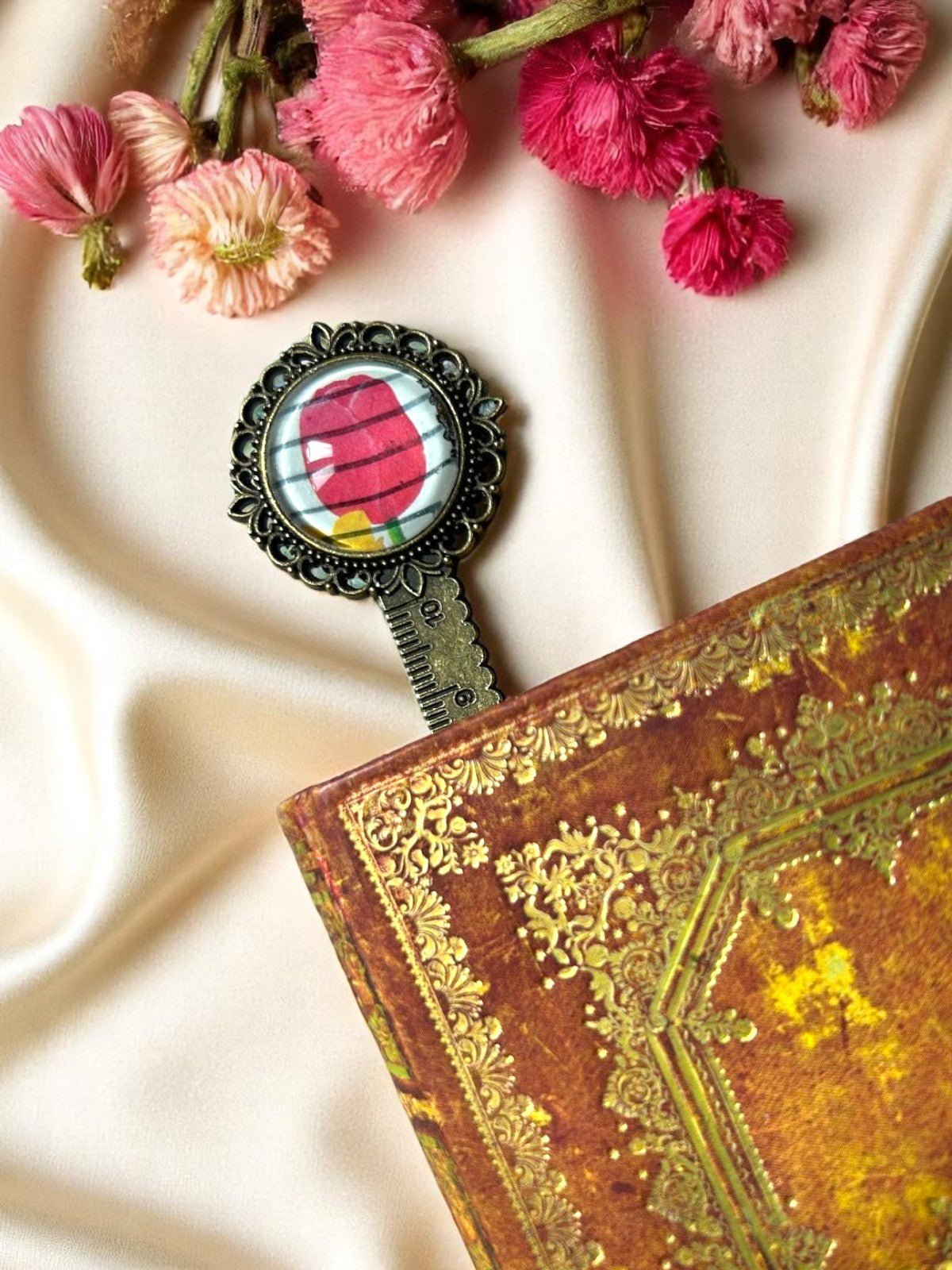 Segnalibro con ciondolo a tulipano appoggiato su un libro dalla copertina dorata